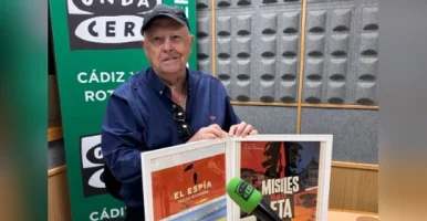 Jaime Rocha en los estudios de Onda Cero Cádiz sosteniendo los carteles del documental El Espía y de la serie Misiles para la ETA, junto a un micrófono de Onda Cero